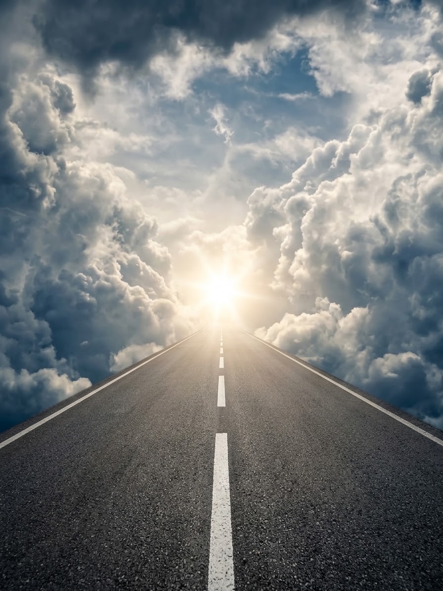 Une route droite qui file vers un ciel de nuages percé par la lumière du soleil